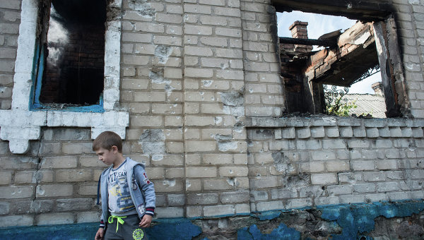 Ребенок у разрушенного в результате обстрела дома в поселке Александровка Донецкой области. Архивное фото