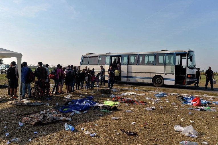 Мигранты выстраиваются на борт автобуса для поездки в транзитный центр для мигрантов на границе между Венгрией и Сербией