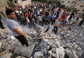 Палестинцы стоят рядом с обломками дома, разрушенного израильскими войсками в городе Дженин