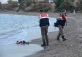Турецкие полицейские рядом с телом маленького сирийского мигранта, который утонул вместе с другими мигрантами, когда их лодка перевернулась.