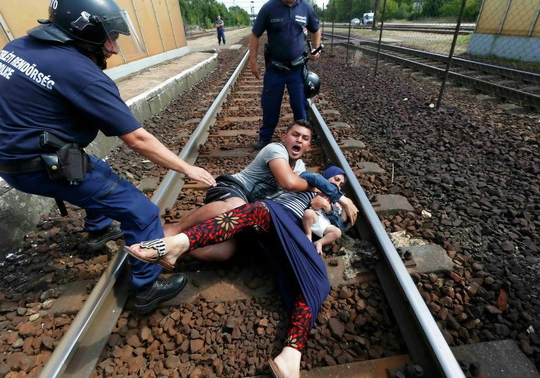 Венгерские полицейские и семья мигрантов, которая хотела убежать на железнодорожной станции в городе Бичке, Венгрии