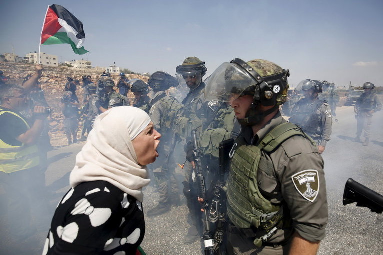 Палестинская женщина спорит с израильским пограничником во время акции протеста против еврейских поселений в деревне Салех на Западном берегу Наби