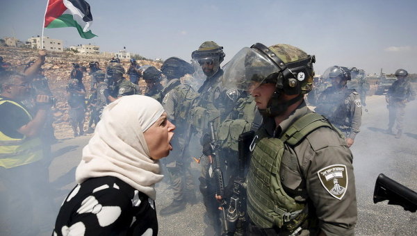 Палестинская женщина спорит с израильским пограничником во время акции протеста против еврейских поселений в деревне Салех на Западном берегу Наби