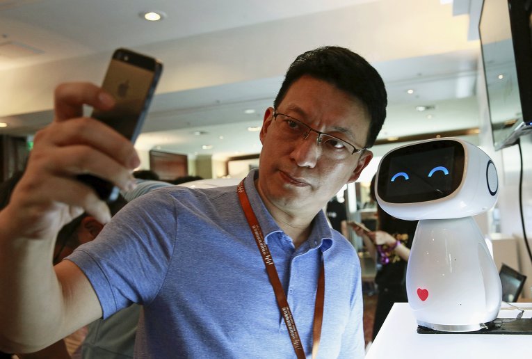 Китайская компания Baidu, предоставляющая различные веб-сервисы,  представила робота Xiaodu, с которым посетитель IT-выставки делает фото.