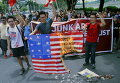 Активисты, осуждая предстоящие встречи Азиатско-Тихоокеанского экономического сотрудничества (АТЭС), жгут флаг США во время акции протеста перед зданием посольства США в Маниле