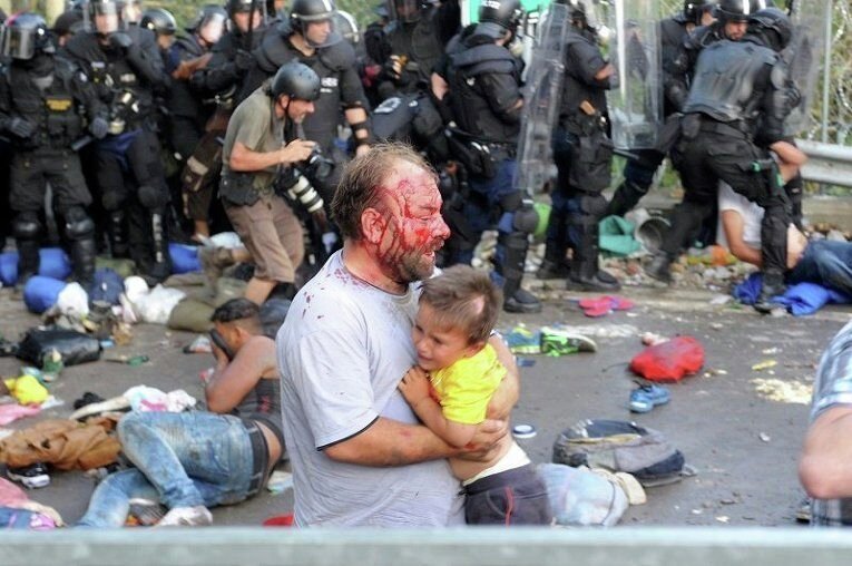 Травмированный мигрант несет ребенка во время столкновений с полицией Венгрии