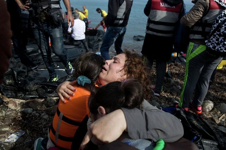 Сирийские беженцы радуются тому, что добрались из Турции на греческий остров Лесбос.