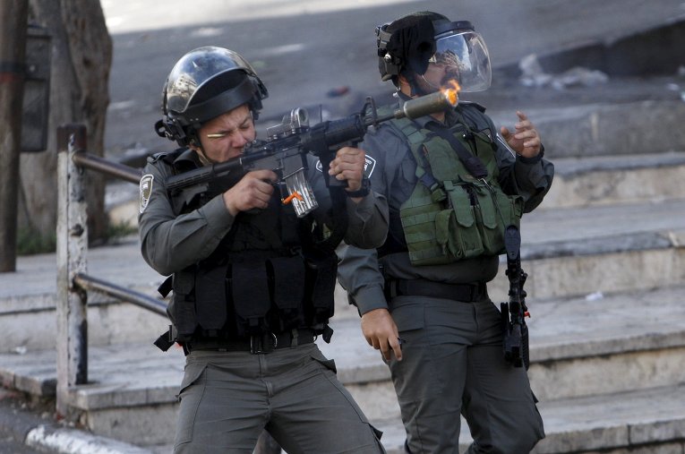 Израильский пограничный полицейский стреляет резиновыми пулями по палестинским демонстрантов во время столкновений в мечети Аль-Акса в Иерусалиме.