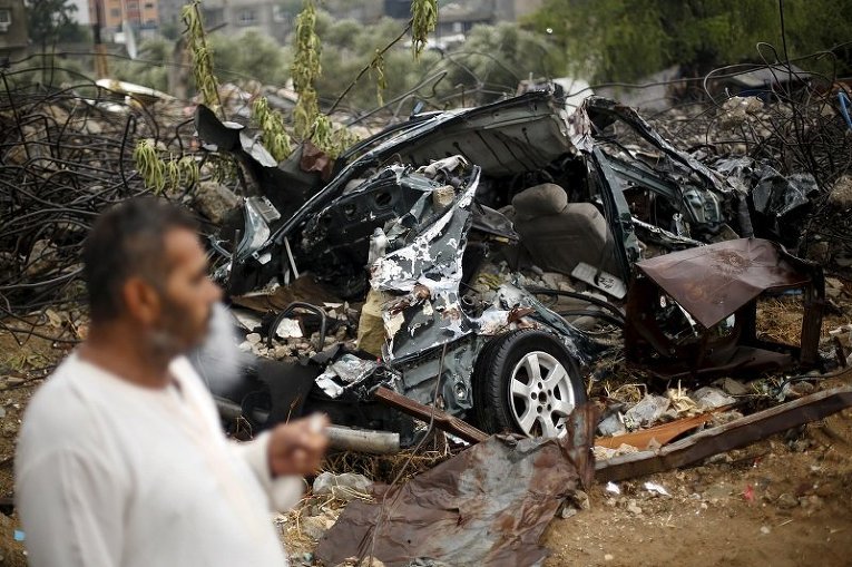 В Палестине мужчина стоит возле машины, уничтоженной в ходе 50-дневной войны с Израилем летом 2014 года