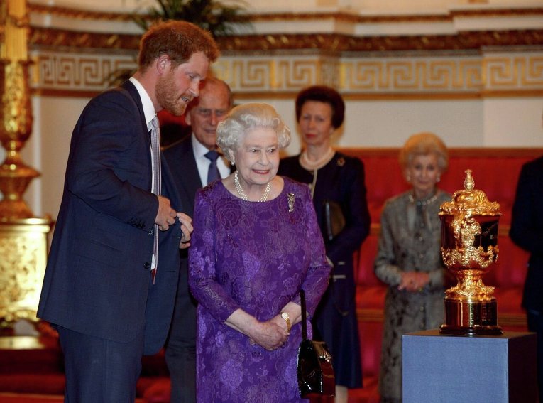 Принц Гарри и королева Елизавета в Букингемском дворце смотрят на Кубок Уэбба Эллиса во время приема