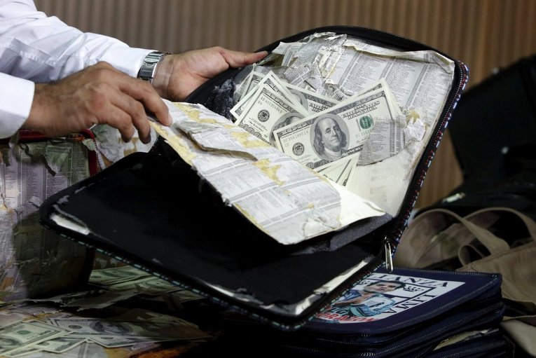 Полиция в Лиме показывает фальшивые доллары, спрятанные в сумке, на конференции.