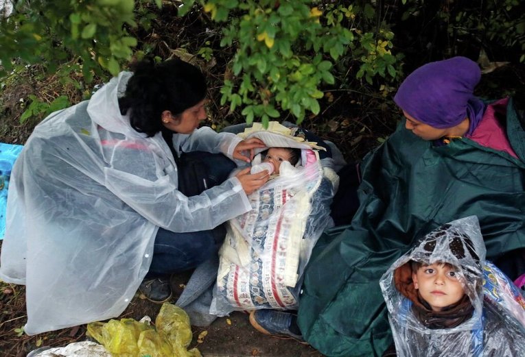 Женщина-мигрантка кормит ребенка в ожидании пересечения границы между Сербией и Хорватией
