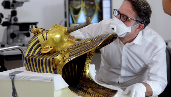 Немецкий реставратор Кристиан Экмана рассматривает бороду золотой маски знаменитого египетского фараона Тутанхамона перед началом реставрационных работ