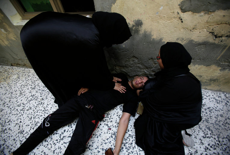 Бахрейнские женщины помогают участнику акции протеста, в которого попал слезоточивый газ