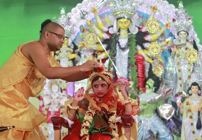 В Индии священник наряжает пятилетнюю девочку для празднования Дурга-пуджа.