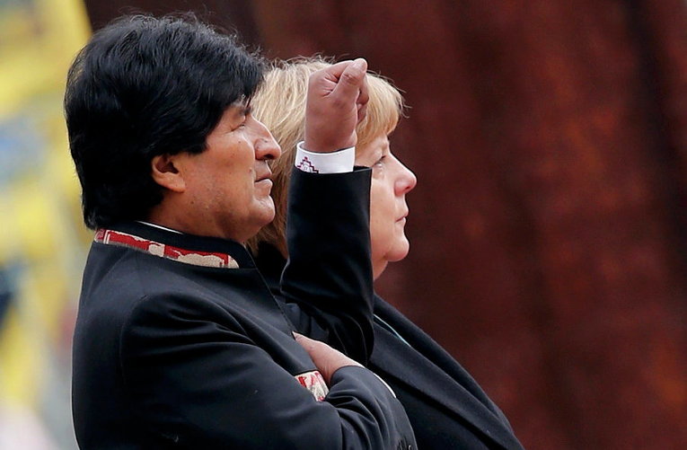 Боливийский президент Моралес слушает боливийский гимн рядом с канцлером Германии Ангелой Меркель в Берлине