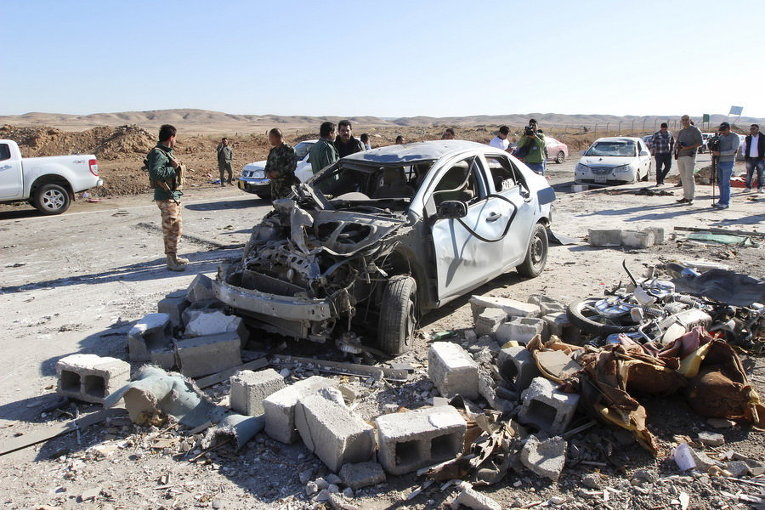 Члены курдских повстанцев у разрушенного автомобиля в городе Дибис, на северо-западе от Киркука