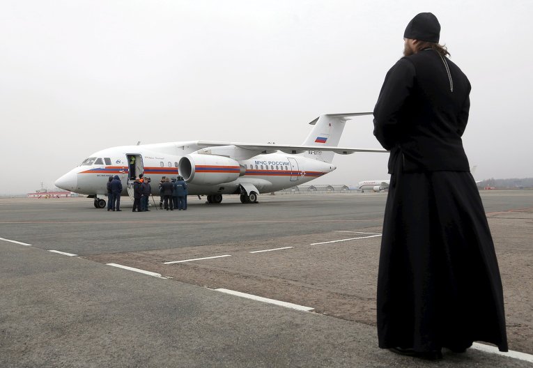 Священник смотрит на самолет МЧС Россиив аэропорту Пулково, который привез останки пассажиров разбившегося Боинга в небе над Египтом.