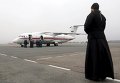 Священник смотрит на самолет МЧС Россиив аэропорту Пулково, который привез останки пассажиров разбившегося Боинга в небе над Египтом.